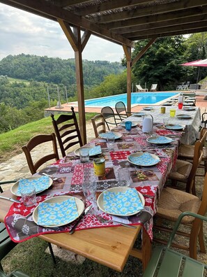 An outdoor dining area with a view of a swimming pool and hills. - Peaceful Holiday House with Private Pool and Panoramic Views: Casa Mumu (Casteletto D’Erro)