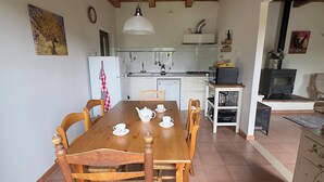 A dining area with a wooden table and chairs, a kitchen in the background, and a fireplace. - Peaceful Holiday House with Private Pool and Panoramic Views: Casa Mumu (Casteletto D’Erro)