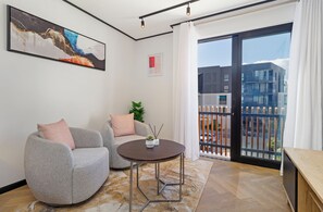 A modern living room with a sofa, a round table, and a painting on the wall. - Modern Studio | Nine Palms Century City (Cape Town)