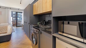 Une cuisine compacte équipée d’un four à micro-ondes Bosch, d’un lave-linge et d’un meuble en bois.