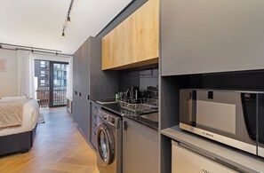 A compact kitchen with a Bosch microwave, a washing machine, and a wooden cabinet. - Modern Studio | Nine Palms Century City (Cape Town)