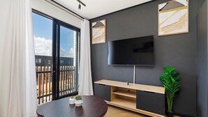 Un salon moderne doté d’un grand téléviseur, d’un meuble de rangement en bois et d’un balcon offrant une vue agréable.