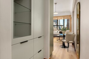 A modern interior with a white cabinet, a dining area with a table and chairs, and a view of the outside through large windows. - Charlie and the Chairman | Modern CBD Studio (Cape Town)