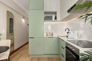A modern kitchen with a microwave, toaster, and oven. - Charlie and the Chairman | Modern CBD Studio (Cape Town)