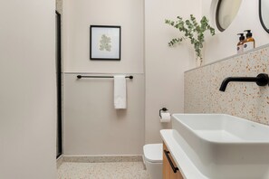 A bathroom with a white sink, toilet, and towel rack. - Charlie and the Chairman | Stylish Studio (Cape Town)