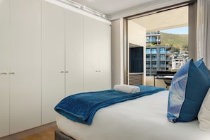 Ein Schlafzimmer mit Bett, Fenster und Blick auf Gebäude.
