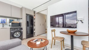 A modern apartment with a kitchen, a dining area with a round table, and a living room with a sofa. - One Rosebank | Slow Luxury, Perfected (Johannesburg)