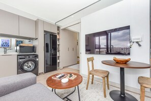 A modern apartment with a kitchen, a dining area with a round table, and a living room with a sofa. - One Rosebank | Slow Luxury, Perfected (Johannesburg)