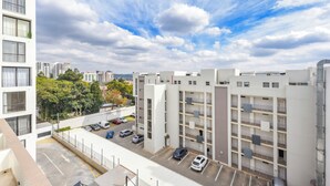 A multi-story parking garage with several cars parked, surrounded by modern buildings and a clear sky. - One Rosebank | Slow Luxury, Perfected (Johannesburg)