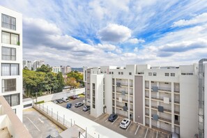 A multi-story parking garage with several cars parked, surrounded by modern buildings and a clear sky. - One Rosebank | Slow Luxury, Perfected (Johannesburg)