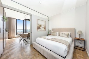 Ein modernes Hotelzimmer mit einem großen Bett, einem Essbereich und Blick durch eine Glastür.