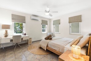 Une chambre à coucher avec un lit, un bureau, une chaise et un ventilateur de plafond.