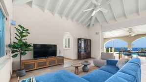 Sala de estar com televisão, sofá e planta em vaso.