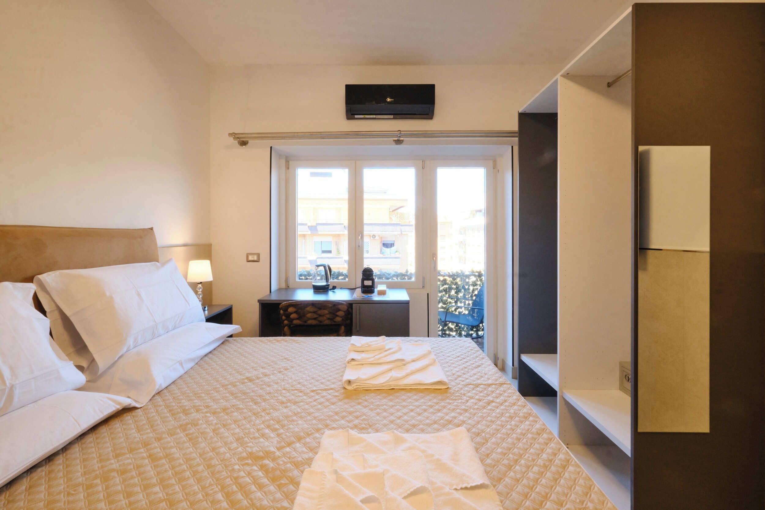Une chambre d’hôtel équipée d’un lit, d’un bureau, d’une chaise, d’une fenêtre donnant sur un paysage agréable et d’un téléviseur.