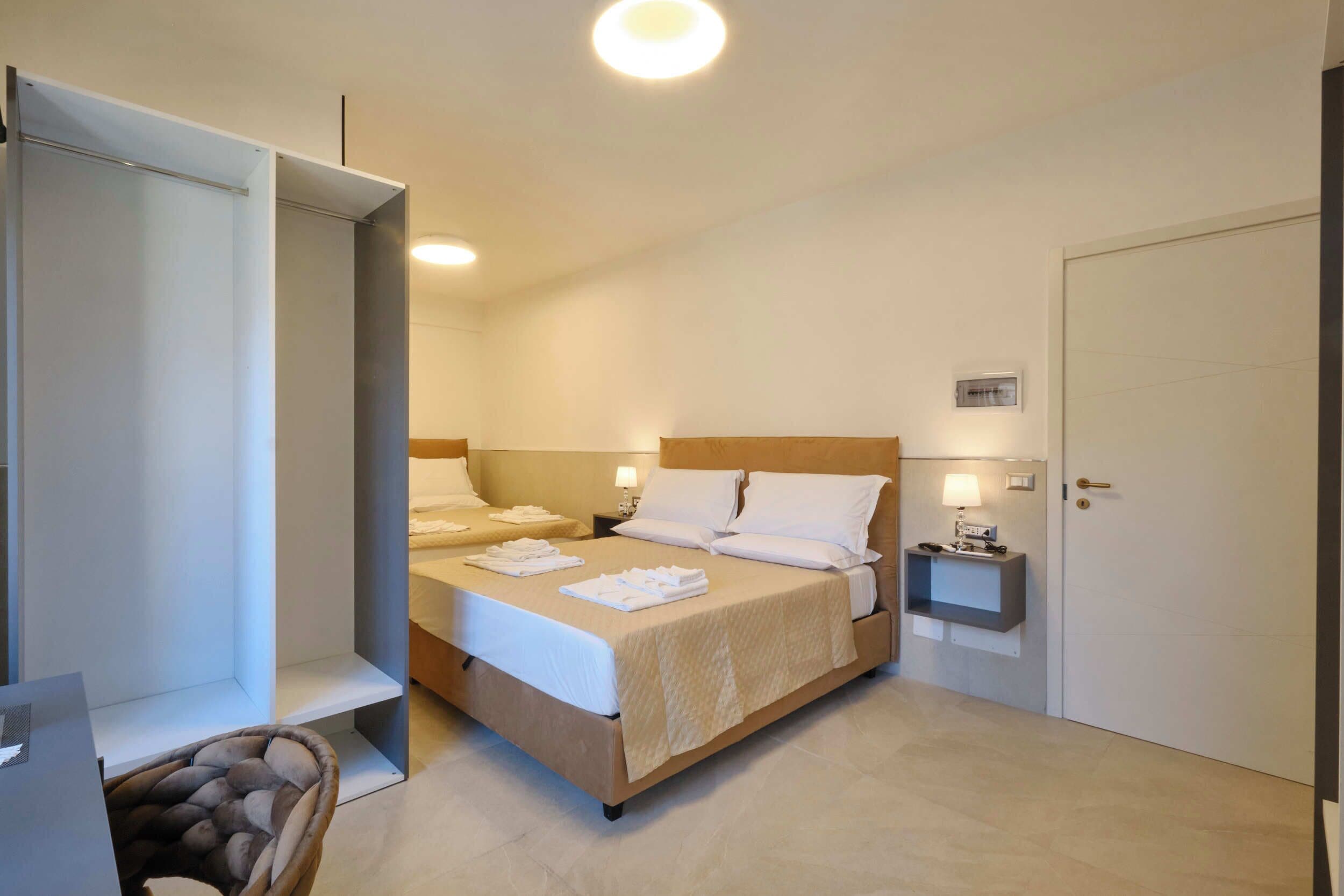 A hotel room with a bed, bedside tables, a lamp, and a door.