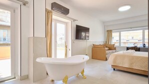Una habitación de hotel moderna con bañera, cama, televisor y balcón.