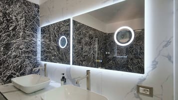 Een badkamer met twee wasbakken, een grote spiegel met ingebouwde verlichting, en marmeren wanden.