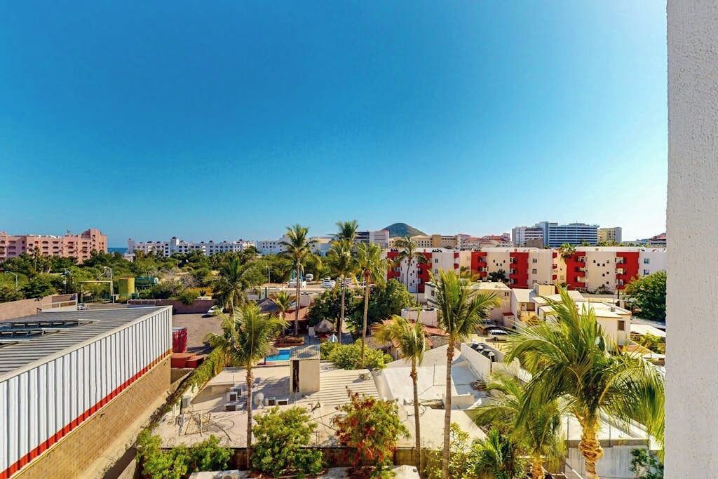 Zona residencial con edificios de varios pisos, palmeras y cielo despejado.