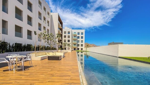 Un hotel moderno con piscina, zona de estar al aire libre y vistas claras del entorno.