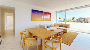 Una sala de estar moderna con una mesa de comedor de madera, un sofá y un ventanal con vistas a la ciudad.