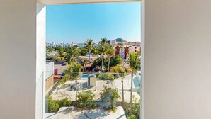 Un balcón con vistas a una zona residencial, con casas y palmeras.