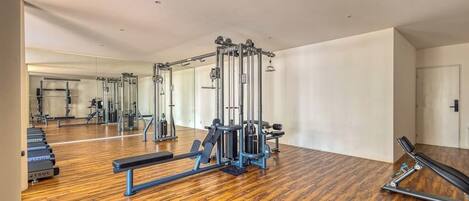 A gym with exercise equipment, wooden flooring, and a large mirror.