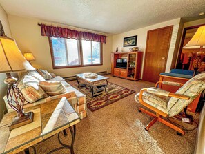 Ein Wohnzimmer mit Sofa, Sessel, Couchtisch und TV-Möbel.