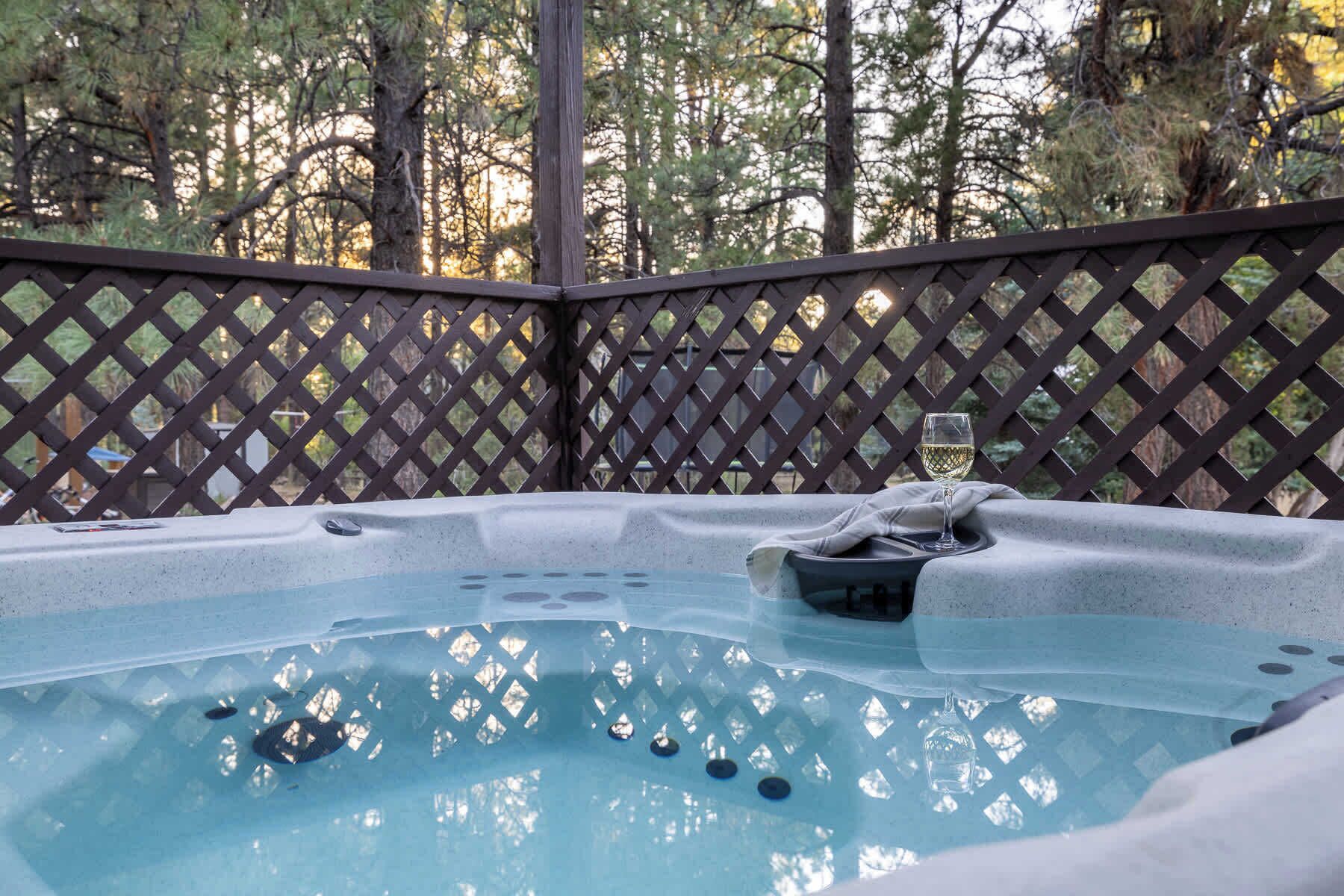 A hot tub with a wooden lattice fence in the background.
