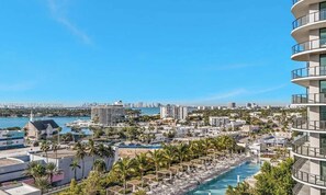 Un hotel con piscina, palmeras y vistas al horizonte de la ciudad.
