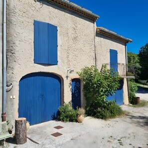 A building with two large blue doors and a smaller arched door, surrounded by greenery and a gravel path. - Apartment 'La Roseraie Des Côtes' with Private Pool, Private Garden and Wi-Fi (Vinsobres)