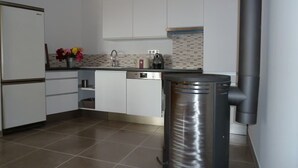 Una cocina moderna con armarios blancos, un cubo de basura de acero inoxidable, una cafetera y un salpicadero de azulejos.