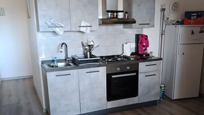 Une cuisine moderne avec des meubles de couleur grise, un évier en acier inoxydable, une cuisinière à gaz et un four encastré.