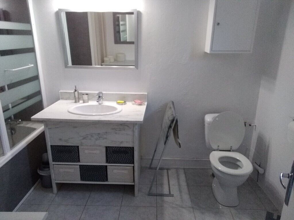A bathroom with a sink, mirror, toilet, and a cabinet.