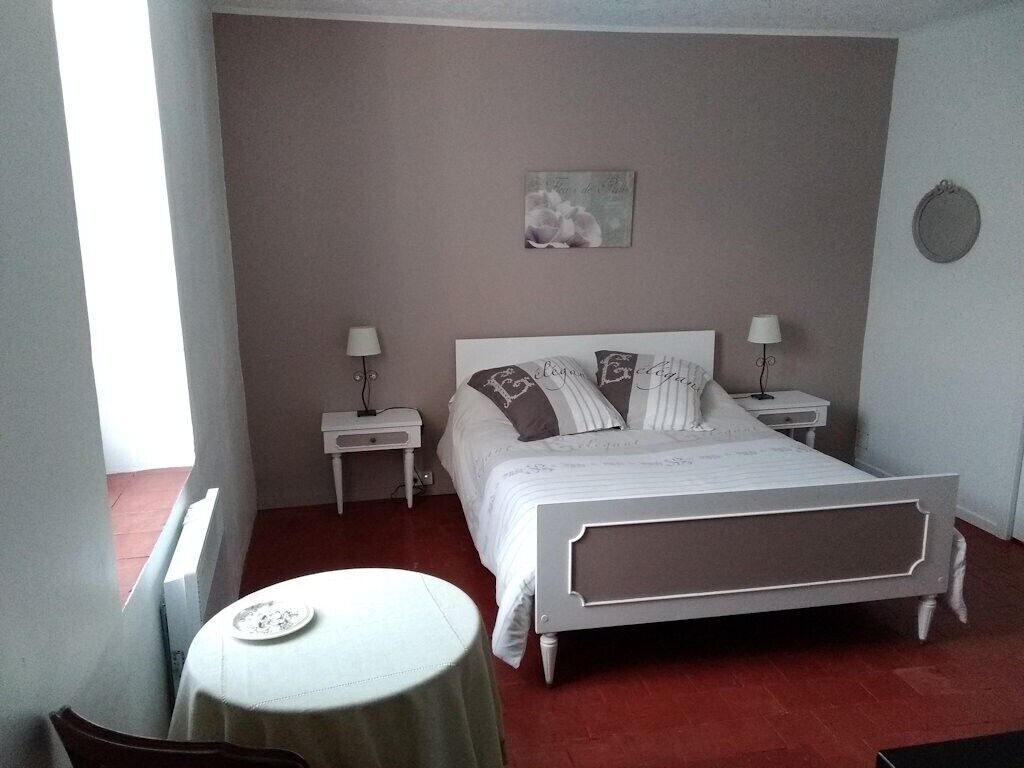 Une chambre à coucher comprenant un lit, des tables de chevet, une petite table et un tableau accroché au mur.