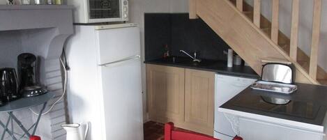 A compact kitchen with a microwave, refrigerator, and a small dining area with a table and chairs.