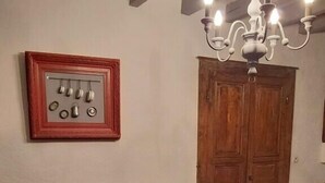 Une pièce avec un canapé sombre, une table rouge, une porte en bois et un lustre.