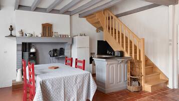 Une cuisine avec une table à manger, des chaises et un escalier en bois.