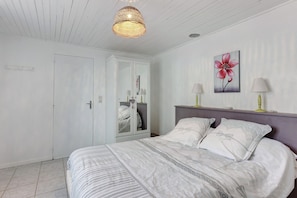 Una camera da letto con un letto, lampade da comodino, uno specchio e un'opera d'arte appesa al muro.