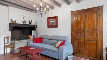 Een woonkamer met een bank, een tafel, een open haard en een houten deur.