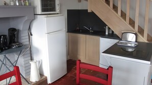 Eine kompakte Küche mit Kühlschrank, Mikrowelle, Kaffeemaschine und einem kleinen Spülbecken.