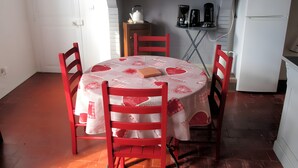 Ein Essbereich mit einem runden Tisch, der mit einer Tischdecke bedeckt ist und von roten Stühlen umgeben wird.