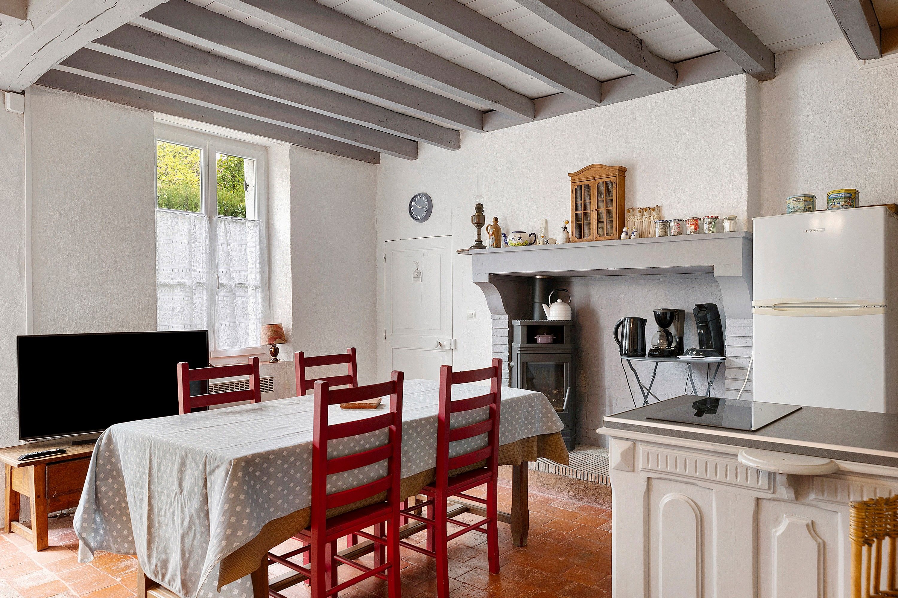 Een gezellige keuken met een eettafel, stoelen, een televisie en een fornuis.