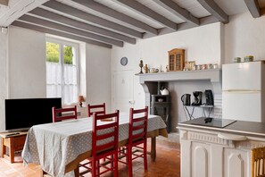 Una cocina acogedora con una mesa de comedor, sillas, un televisor y una estufa.