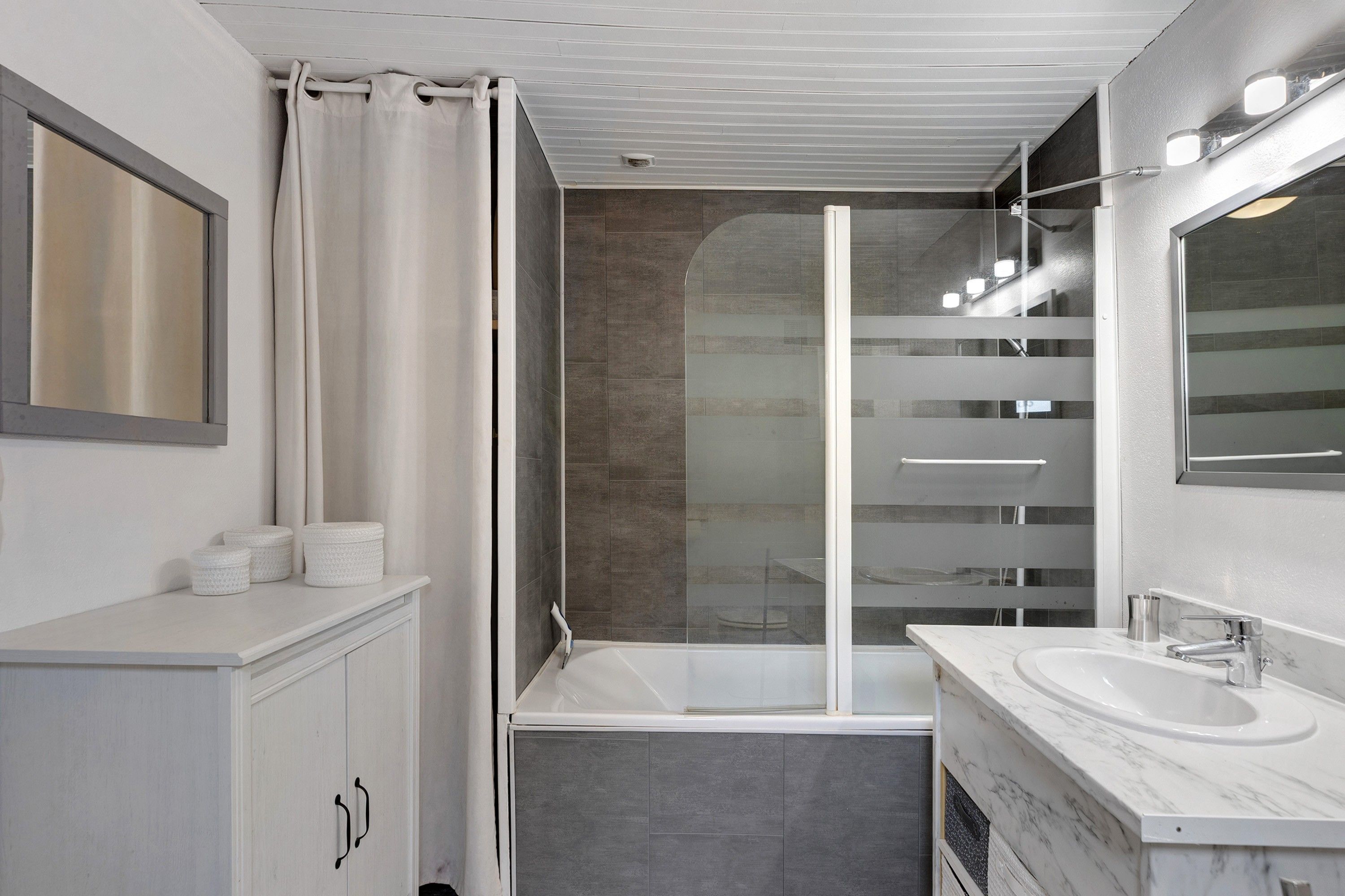 Een moderne badkamer met een bad, een douchecabine van glas en een wastafelmeubel met een wastafel.