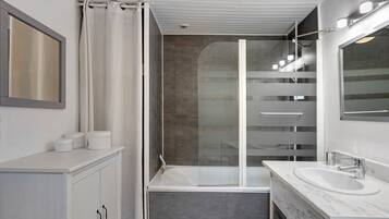 Een moderne badkamer met een bad, een douchecabine van glas en een wastafelmeubel met een wastafel.