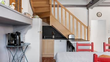Una cucina compatta con una scala in legno, un'angolatura per mangiare e un letto.