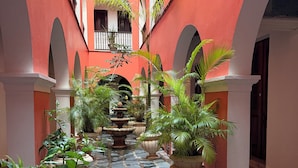 Une cour avec un sol en pierre, des arcades et des plantes en pot.