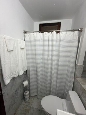 Une salle de bain avec un rideau de douche, des toilettes, un porte-serviettes et un sol en marbre.