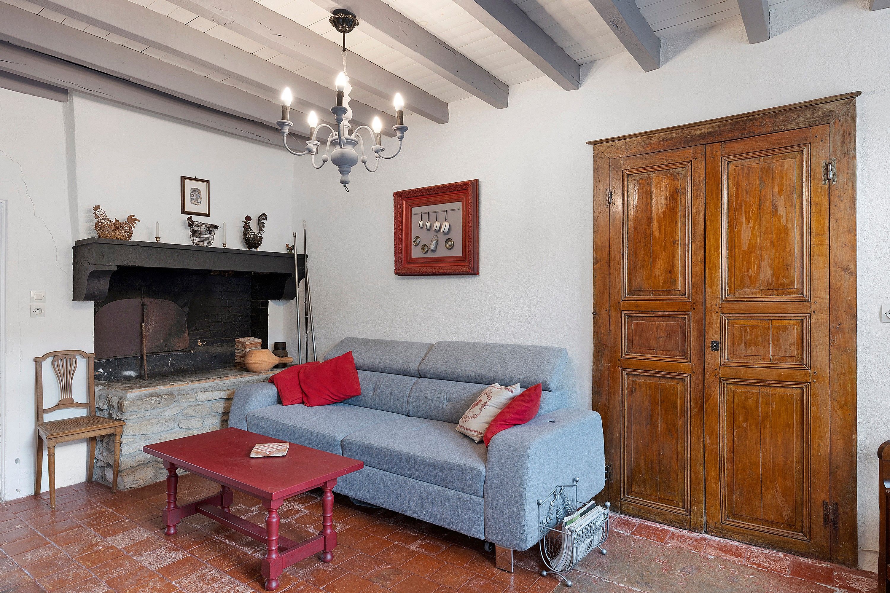Sala de estar com sofá, mesa, lareira e porta de madeira.