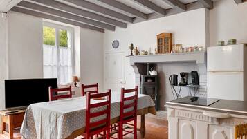 Een gezellige keuken met een eettafel, stoelen, een televisie en een fornuis.